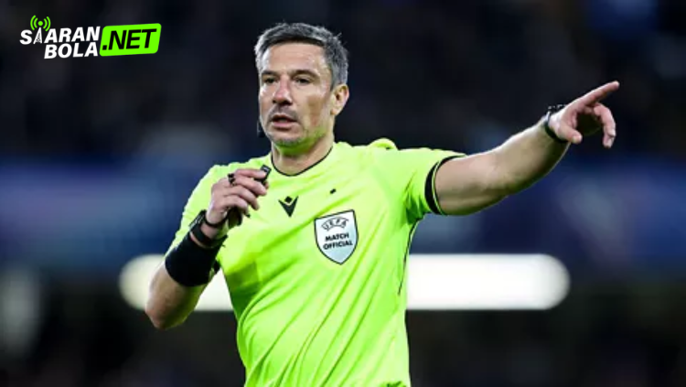 Wasit FIFA mengenakan seragam hitam memberikan isyarat dengan kedua tangan saat memimpin pertandingan sepak bola internasional di stadion.